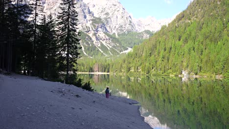 Amplia-Vista-De-Una-Mujer-Disfrutando-De-Una-Vista-Del-Lago-Como-Un-Espejo-Desde-La-Orilla-Y-Croda-Del-Becco-En-El-Fondo