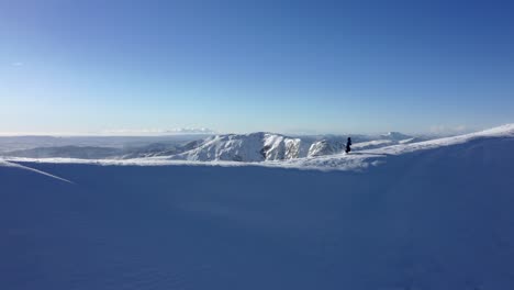 Professional-male-mountaineer-traversing-the-top-of-a-snowy-mountain