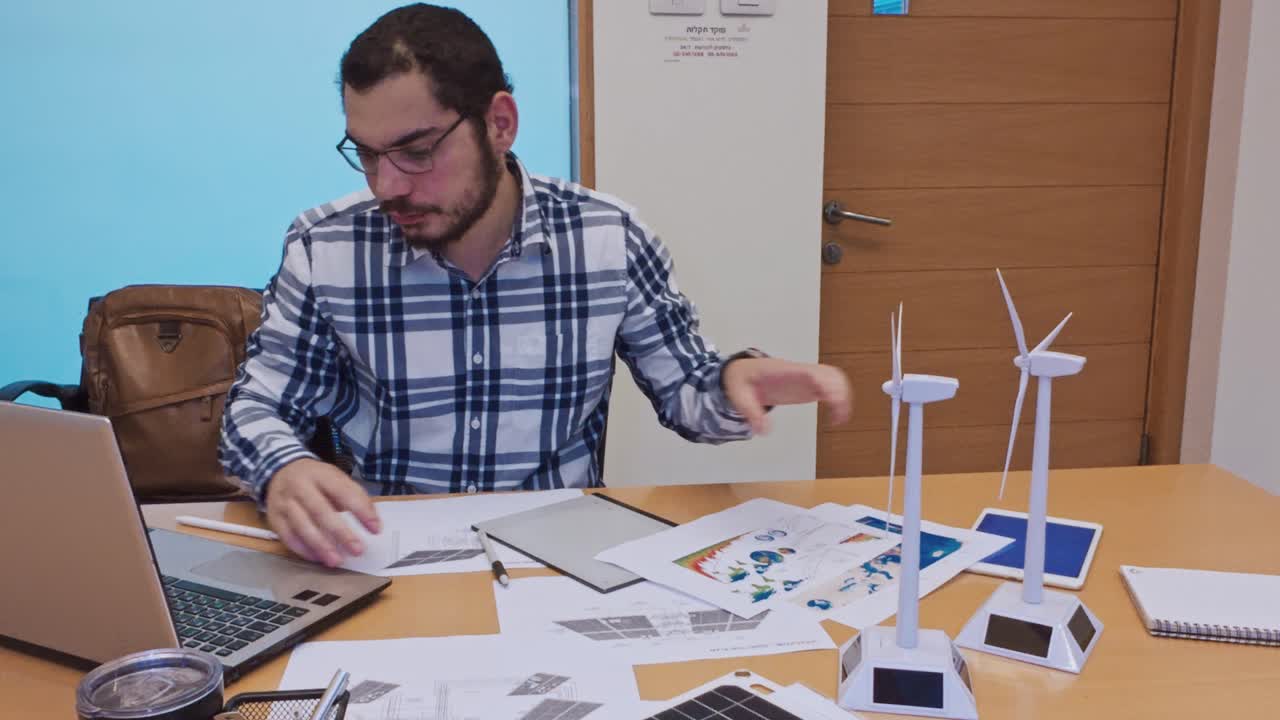 Person working on a laptop with wind turbine models on desk