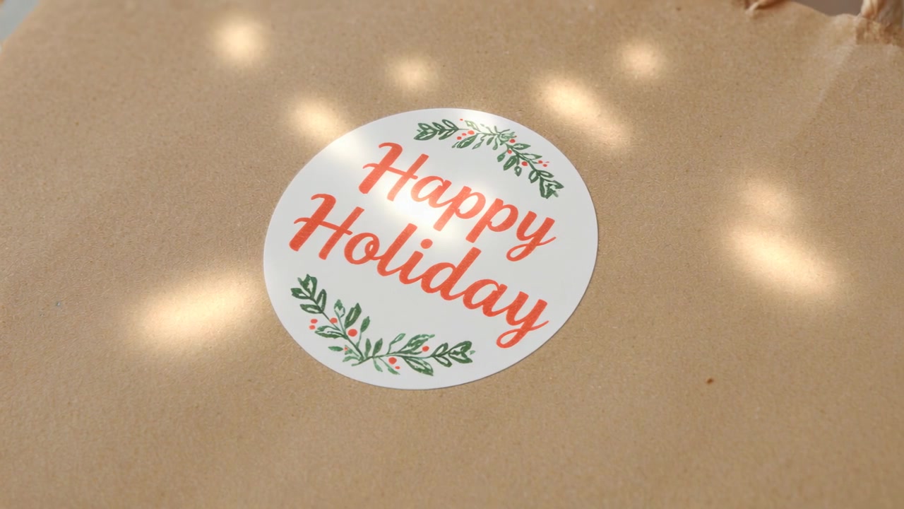 Luminosità crescente, luci soffuse che appaiono intorno a un adesivo bianco su carta kraft che mostra "Buone Feste"