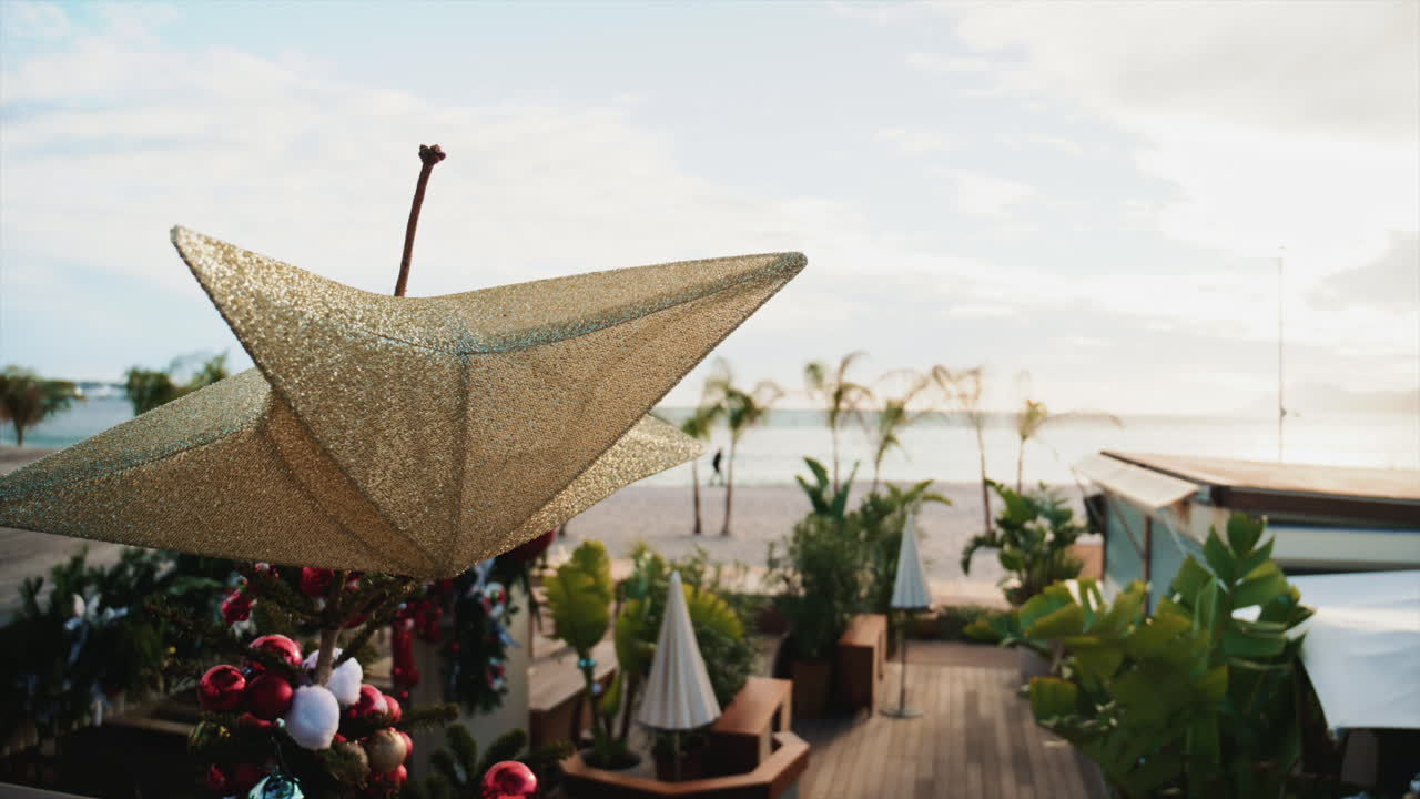 Primo piano di una decorazione natalizia a forma di stella dorata con palme e spiaggia sfocate sullo sfondo