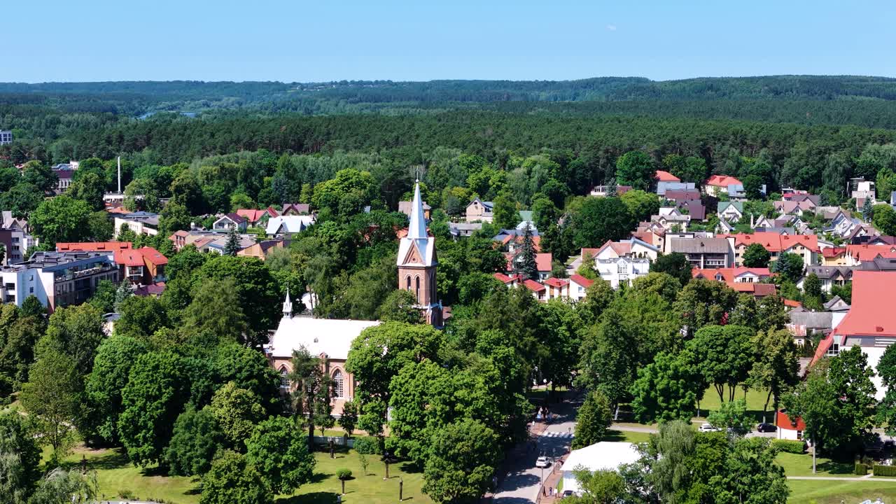 Church tower of Birstonas and green woodland in background, aerial view