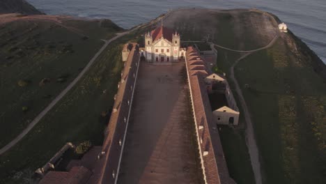 Wide-shot-of-Santuario-de-Nossa-Senhora-do-Cabo-Espichel-during-sunrise,-aerial