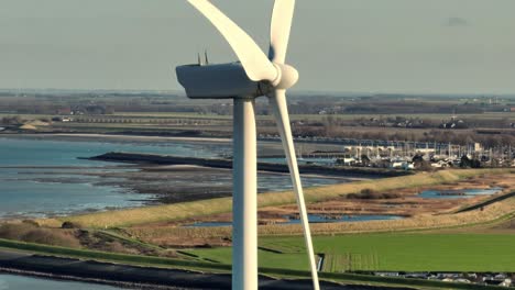 aerial closeup shot of a wind turbine in a rural area in the netherlands at sunset on a sunny day