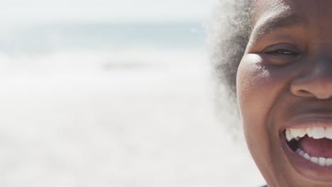 Portrait-of-happy-senior-african-american-woman-smiling-at-beach,-in-slow-motion,-with-copy-space