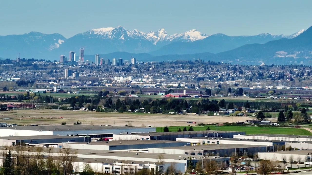 Delta, Richmond, Columbia Britannica, Canada - Una vista ampia dell'area industriale del fiume Fraser con le Montagne Costiere in lontananza - Ripresa con drone in orbita.