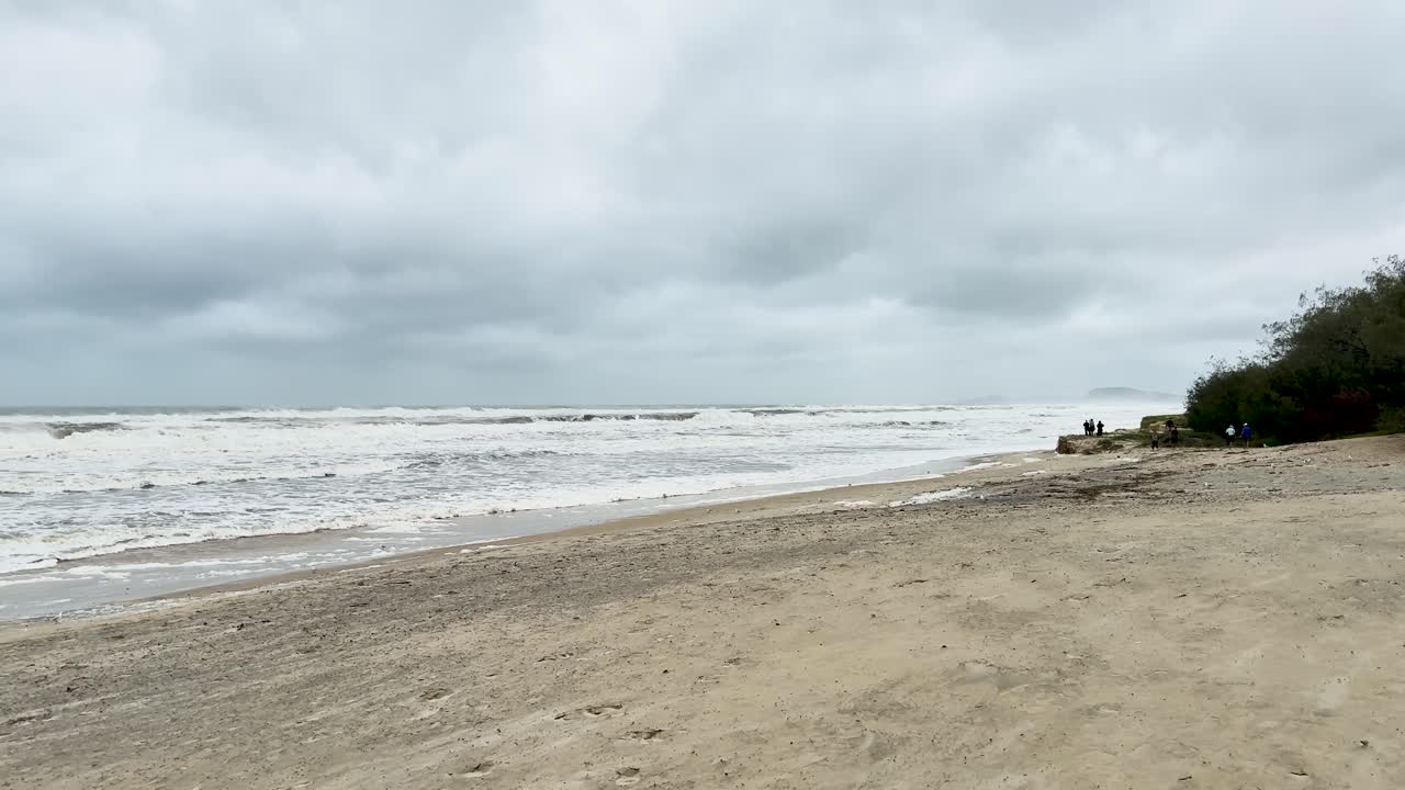 흐린 하늘 아래의 황폐한 해변, 격렬한 파도, 사이클론 알프레드에서 기분 좋고 극적인 해안 분위기를 포착합니다.