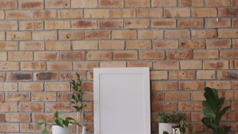 wooden frame with copy space on white background with plants on desk against brick wall