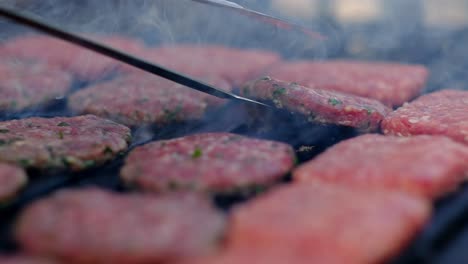 Meatballs-cooked-on-the-barbecue-are-turned-with-tongs-close-up