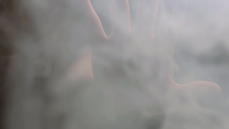 outstretched hand in smoke fumes against dark background