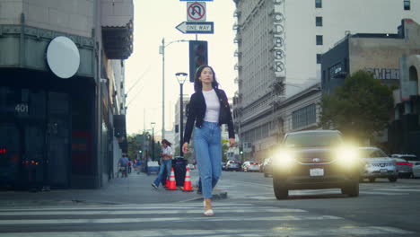 asian girl going crosswalk modern city. tourist woman crossing town road.