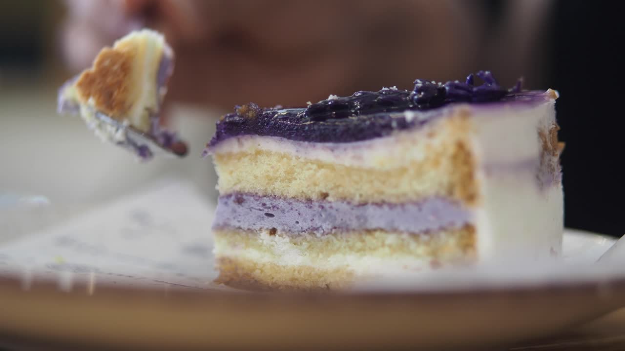 Primo piano di un cucchiaio che taglia una fetta di torta viola a strati