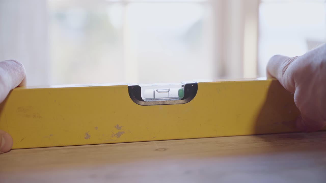 primer plano de un nivel de burbuja, persona que comprueba si una mesa está nivelada correctamente
