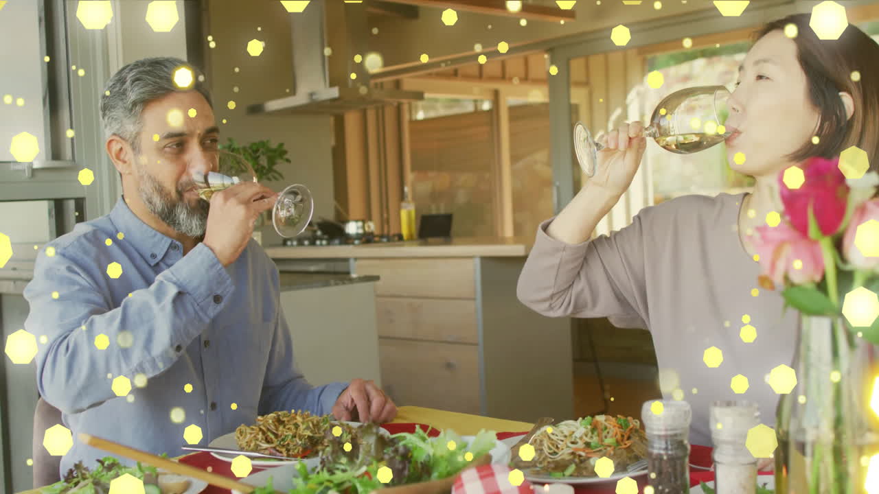 animación de puntos de luz sobre una pareja diversa cenando y bebiendo vino en casa