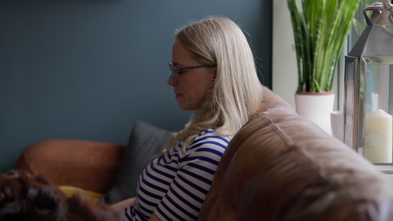 Woman relaxing on couch with dog and plant