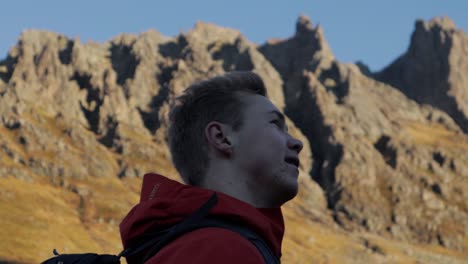 primer plano de seguimiento de un excursionista masculino disfrutando del hermoso paisaje montañoso durante el día soleado y el cielo azul en noruega