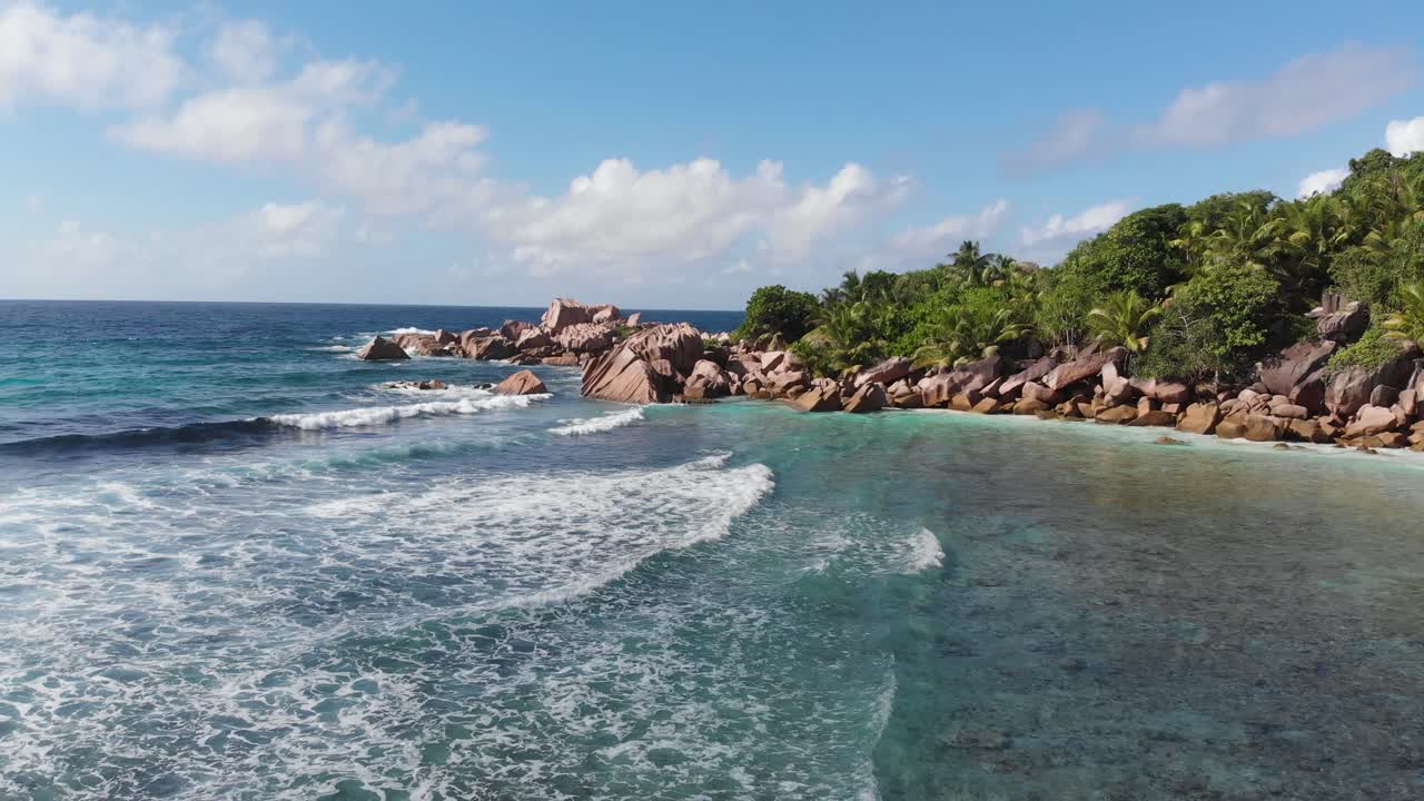 vista aérea siguiendo las olas rodando hacia las playas blancas y despobladas de anse coco, petit anse y grand anse en la digue, una isla de las seychelles