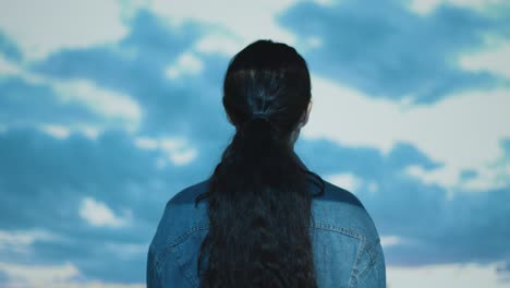 woman visiting immersive art exhibition interacting with images of clouds being projected onto her body