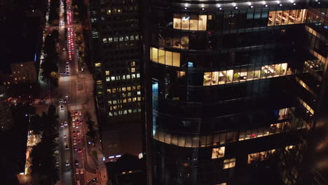 Modernes-Bürohochhaus-Mit-Glänzender-Fassade,-Die-Lichter-Reflektiert.-Kippen-Sie-Nach-Oben-Und-Enthüllen-Sie-Eine-Lange,-Gerade,-Belebte-Straße.-Warschau,-Polen