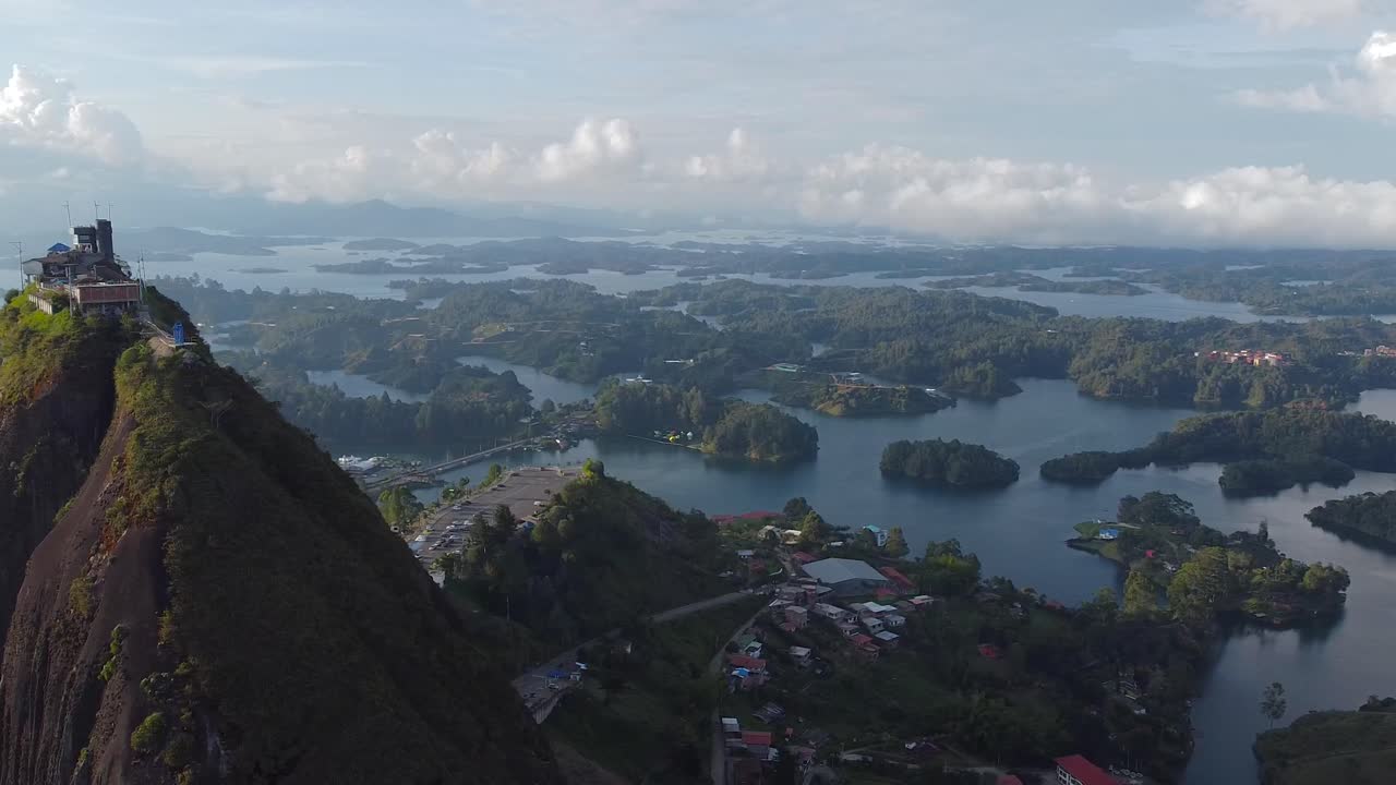 sobrevuelo de drones de una enorme montaña en colombia llamada guatape con muchos lagos pequeños en el fondo