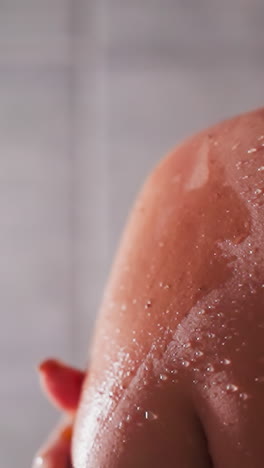 woman applies scrub on shoulder in shower unit closeup. lady exfoliates dry skin with homemade cosmetic product in bathroom. spa relaxation at home