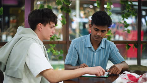 teen wearing blue shirt guiding colleague hand placement of black ink on pencil sketch paper with methodical instruction and focused collaboration capturing dynamic creative teaching moment