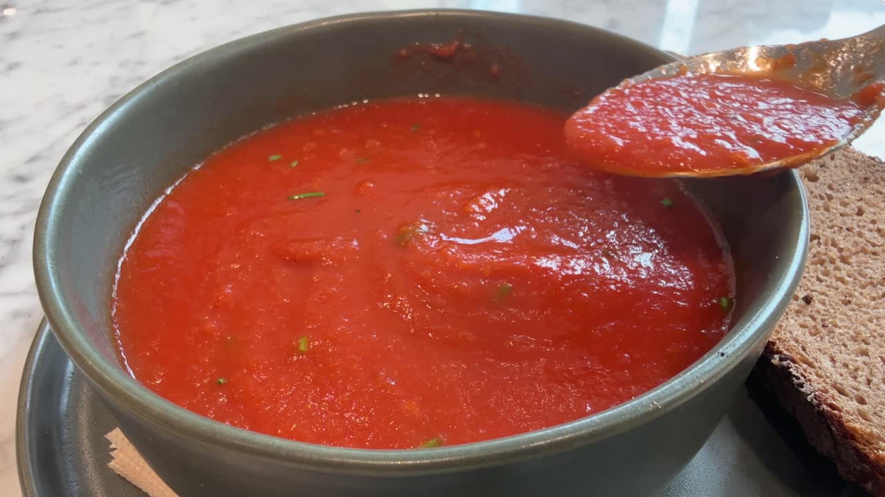 Eating a fresh hot vegetable soup with brown bread close up with personal perspective