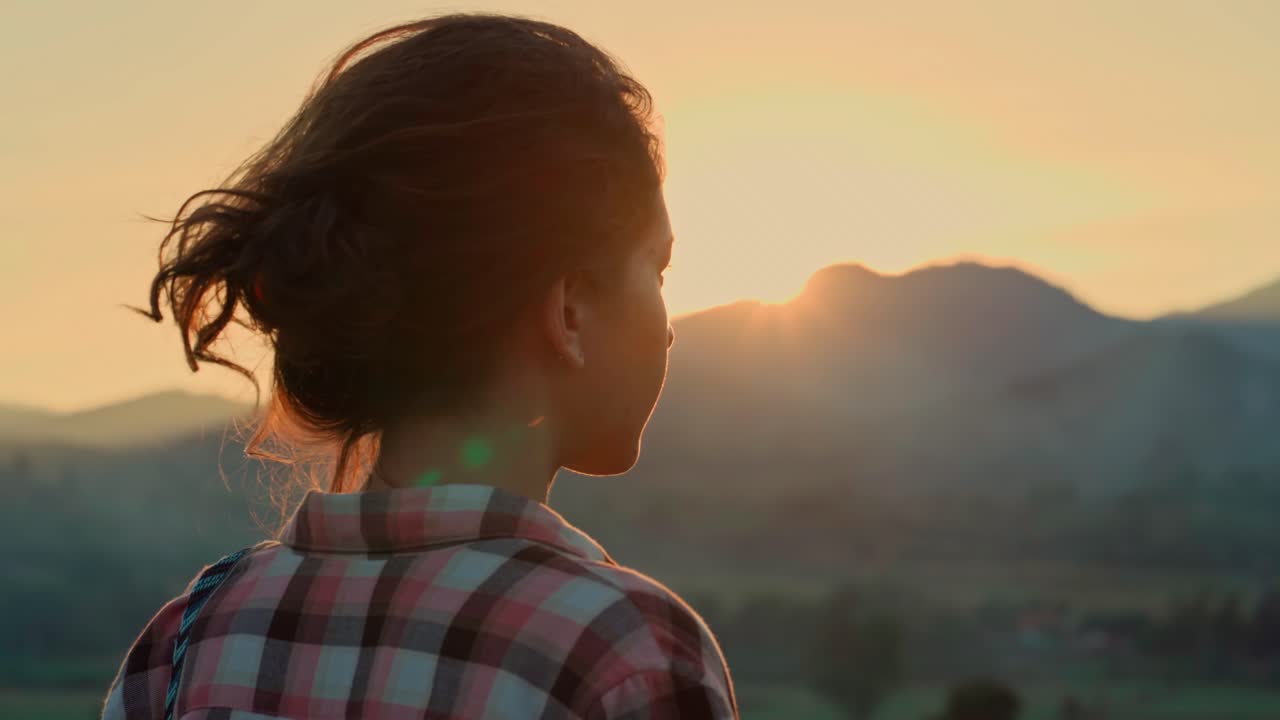 Joven contemplando un atardecer dorado sobre las montañas
