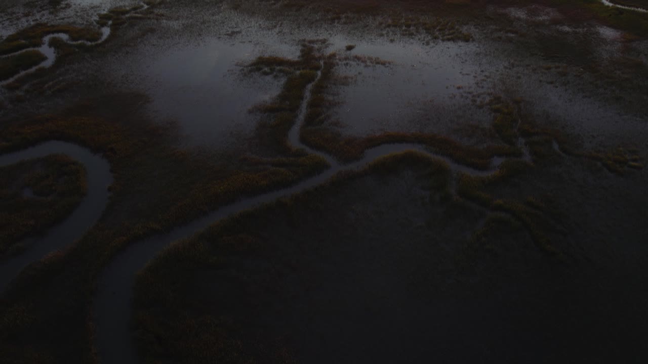 dolly aéreo de alto ángulo a lo largo de los humedales pantanosos con el río serpenteante en la isla de chincoteague virginia, cámara lenta