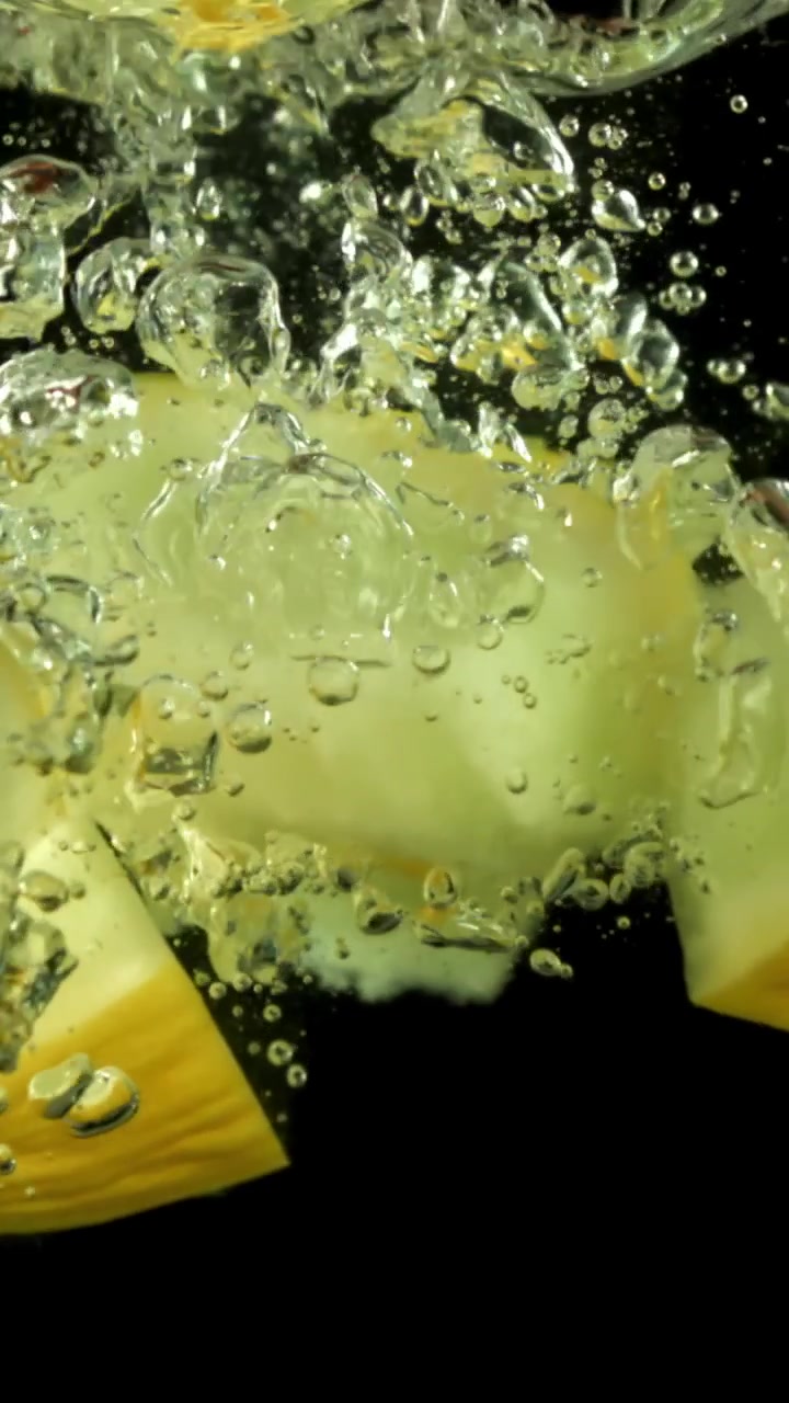 Fresh Yellow Melon Slices Dropping into Water with Bubbles