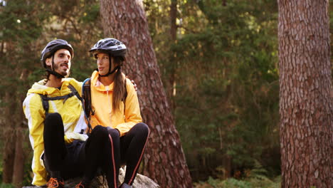 mountain biking couple sitting on a rock in the forest