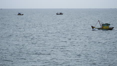 Traditional-Vietnamese-fishing-boat-sailing-in-open-ocean,-calm-waves-gloomy-day