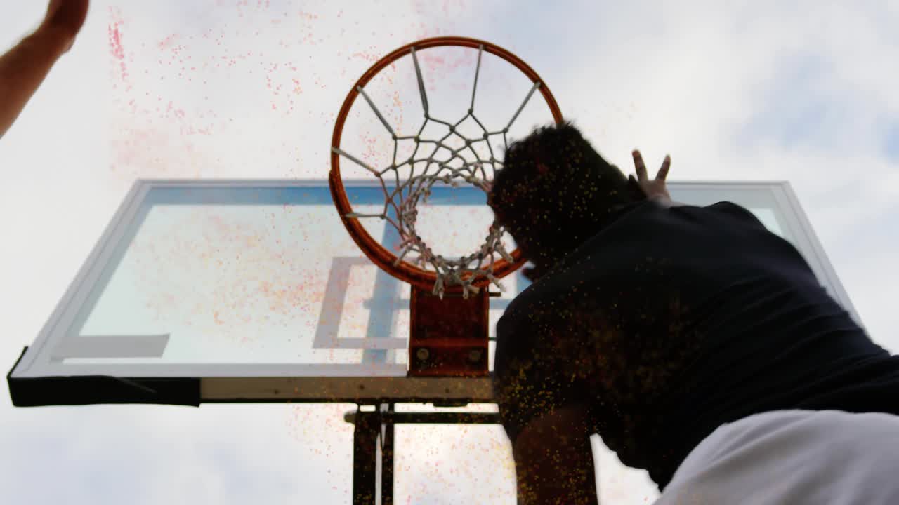 Static portable hoop players taking turns entering and dunking ball showing orange powder effect