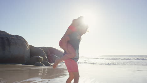 hombre atractivo dando novia piggyback pareja disfrutando de la naturaleza en la playa
