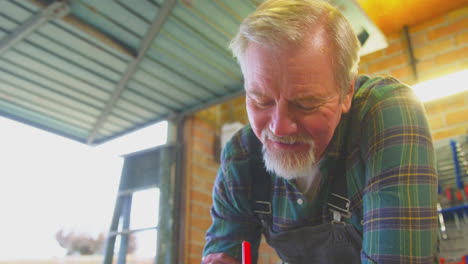 Senior-Male-Carpenter-In-Garage-Workshop-Sketching-Out-Design-On-Paper