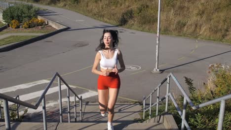 sportive girl running up outdoors flight of stairs - frontal slomo