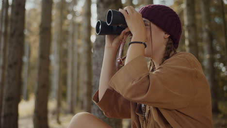 Mujer-Joven-Buscando-A-Través-De-Binoculares-En-El-Bosque.