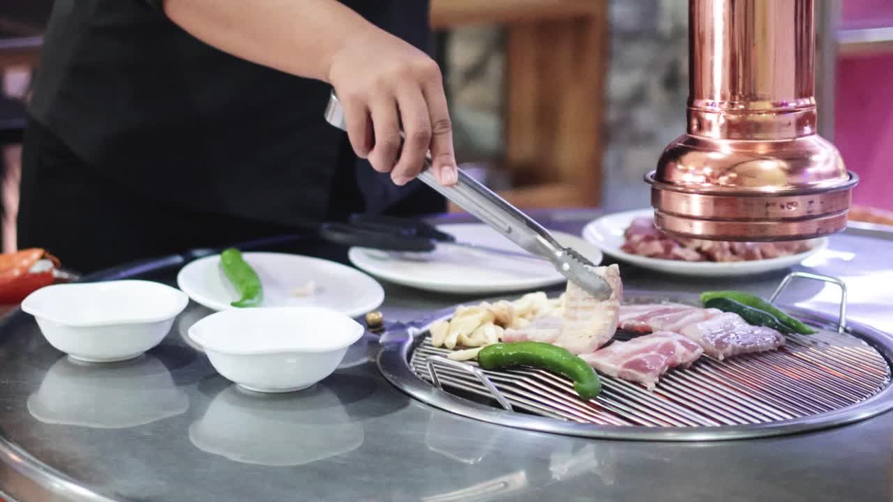 셰프는 다양한 고기와 채소를 그릴로 조리합니다.