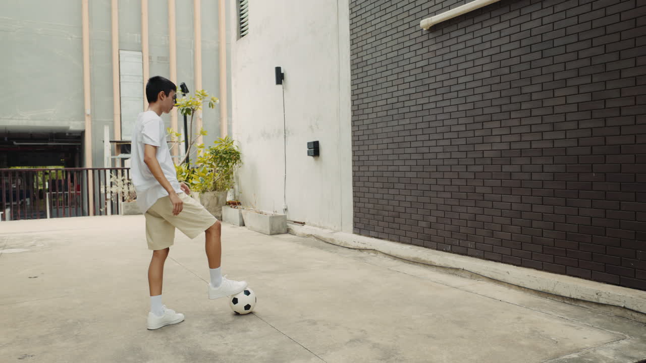 Boy playing soccer against a wall