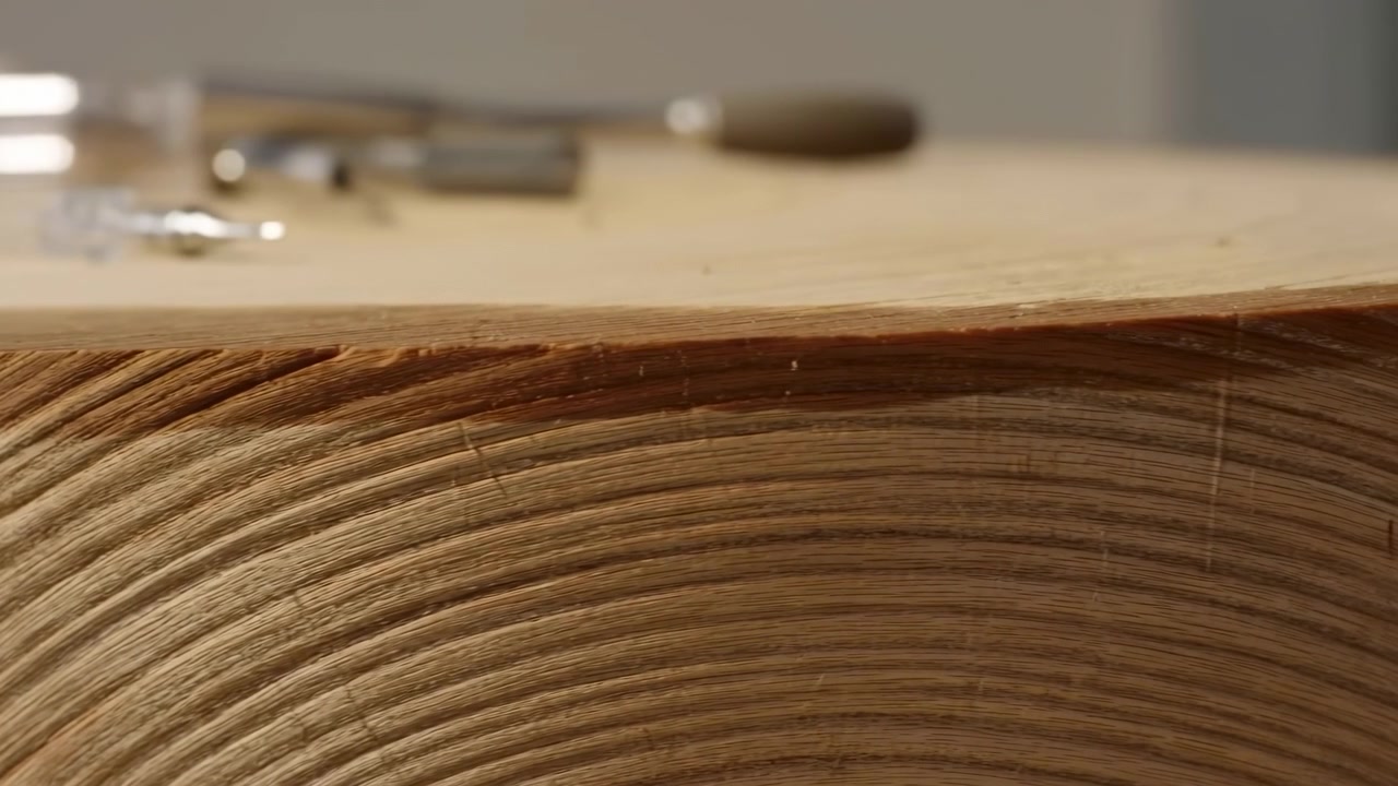 Una bobina di legno con attrezzi metallici è osservata in un ambiente di lavoro interno con vista dall'alto, che mostra un'atmosfera neutra e materiali marrone-argento. Questa scena evidenzia l'artigianato e gli strumenti da officina.