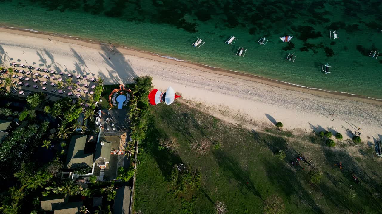 Stunning aerial perspective of turquoise coastal waters in Bali, dotted with fishing boats and vivid kites flying high above the sandy shore beneath the tropical sunshine