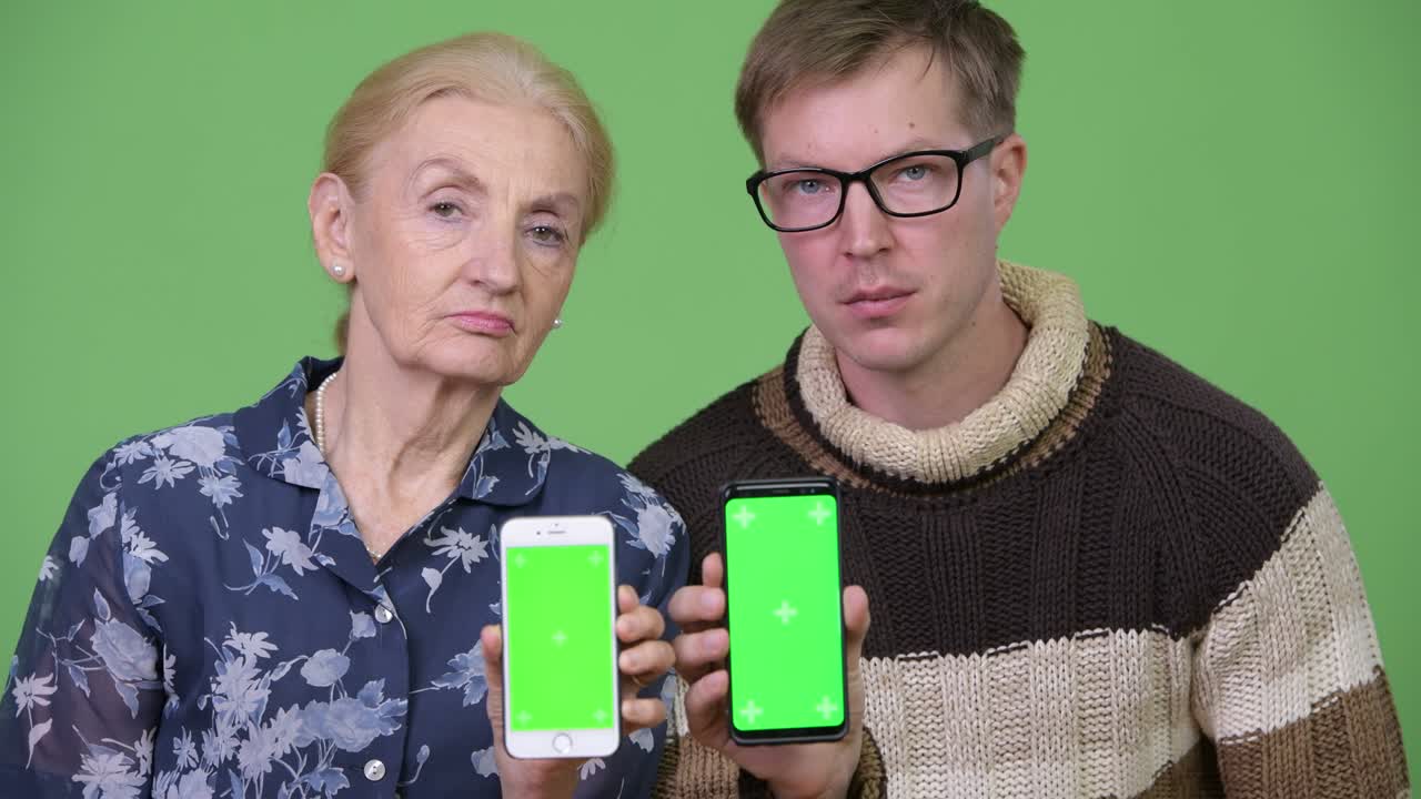 Happy grandmother and grandson showing phones together