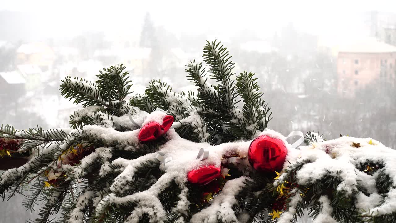 Juletræsgrene pyntet med legetøj under sne.