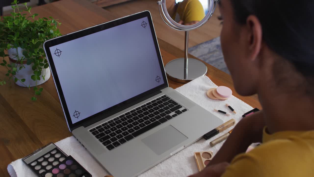 Mixed race gender fluid person sitting at desk working from home using a laptop