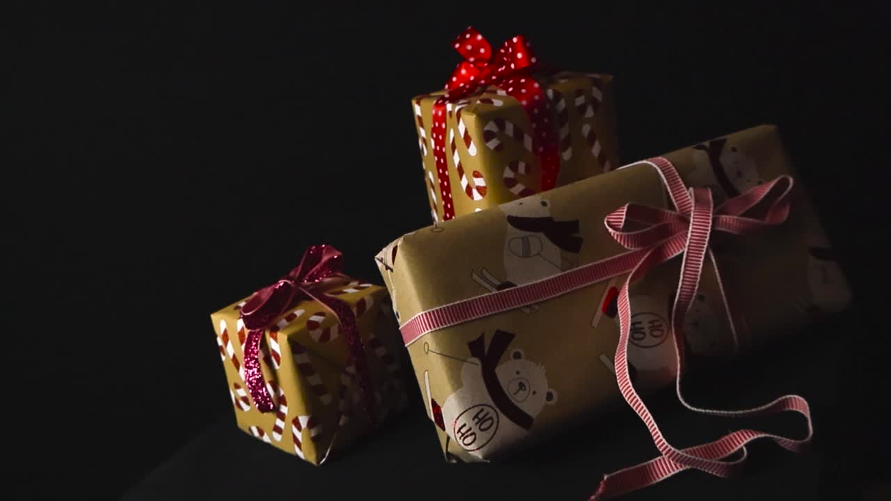Splendidi regali di Natale o pensierini per le feste con carta da regalo colorata a forma di bastoncini di zucchero e nastri rossi posizionati su uno sfondo nero da studio