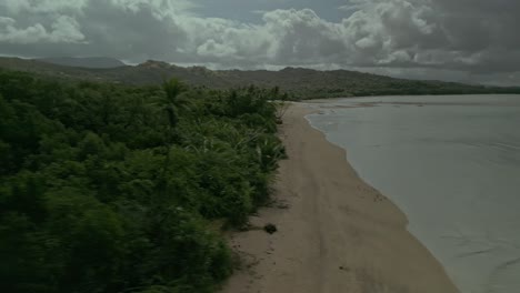 Rising-aerial-from-calm-sea-to-vast-green-woodlands-in-the-Philippines