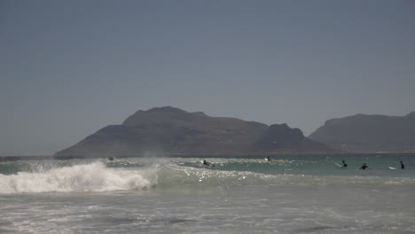 cámara lenta de surfistas a lo largo de la costa en sudáfrica