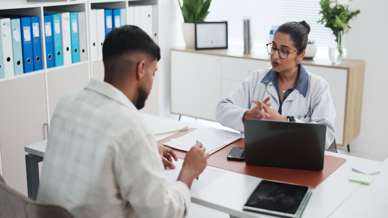 Female Doctor Explaining Paperwork to Male Patient During Consultation