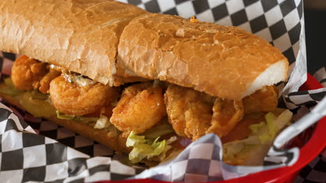 Cajun-fried-shrimp-poboy-on-checkered-black-and-white-paper-in-basket,-slider-close-up-4K