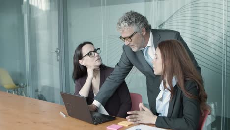 grey-haired senior manager explaining presentation on laptop